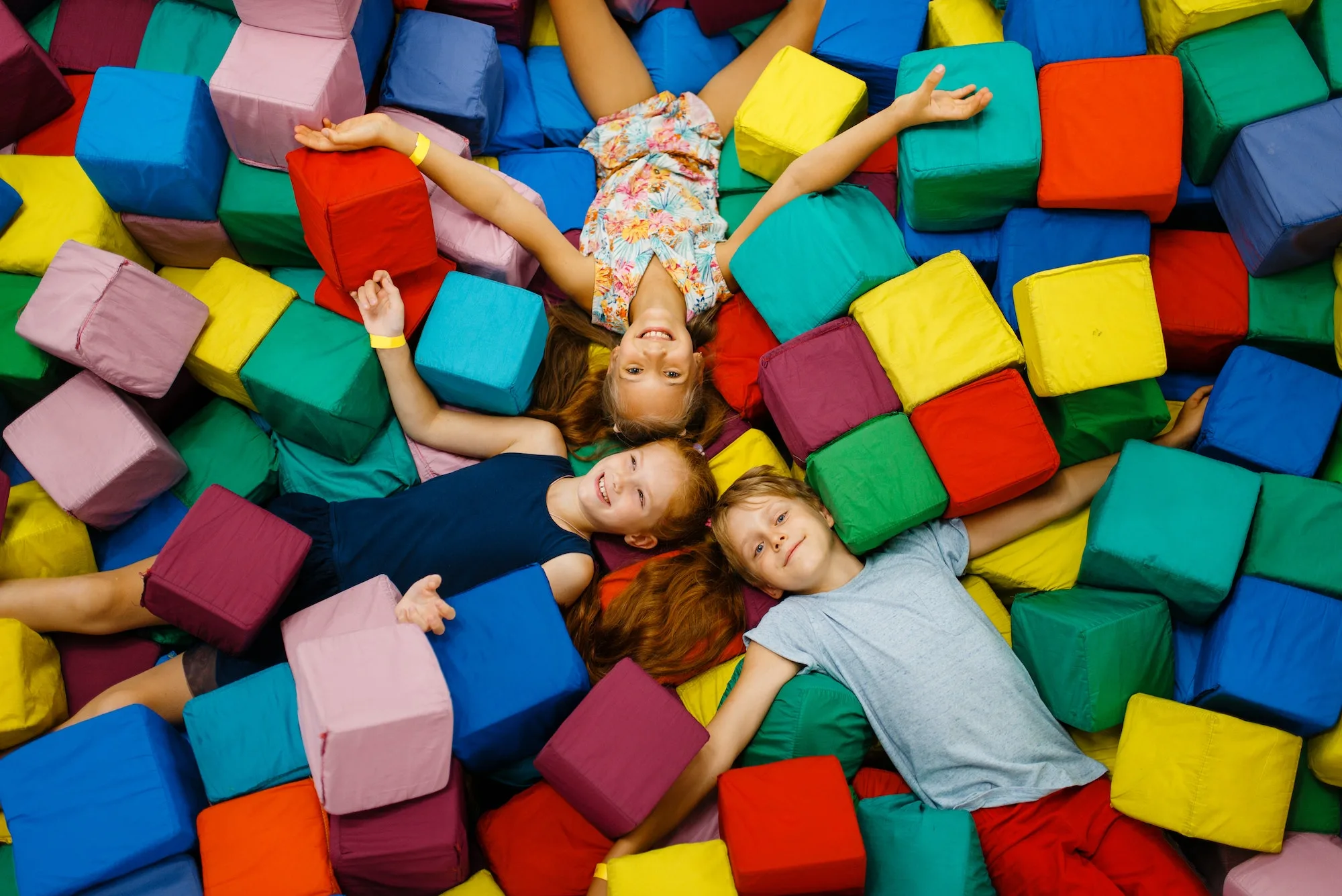 Happy children lying in soft cubes, playroom