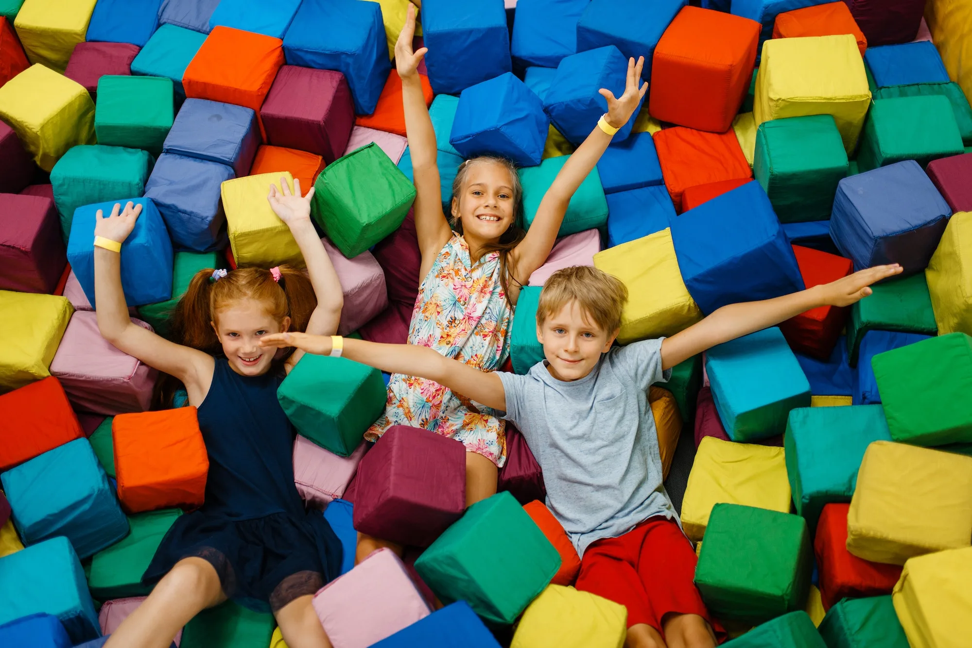 Happy children lying in soft cubes, playroom